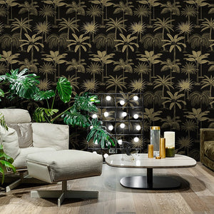 Modern living room displaying tropical non woven wallpaper illustrated with gold palm trees on a black background