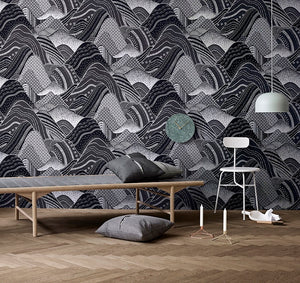 Stylized rolling mountain patterned non woven wallpaper in charcoal and black displayed in a room with contemporary decor