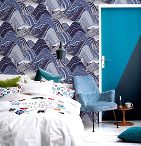 Stylized rolling mountain patterned non woven wallpaper in blue on a bedroom wall